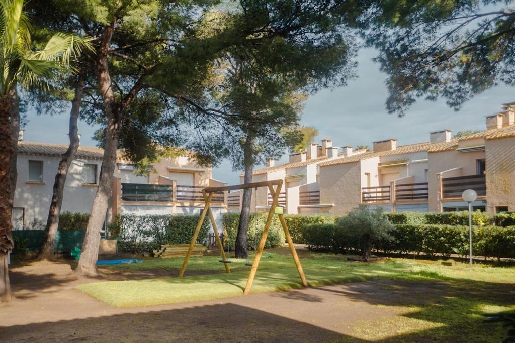 une balançoire dans un parc en face d'un bâtiment dans l'établissement Aux portes de la Nature, au Cap d'Agde