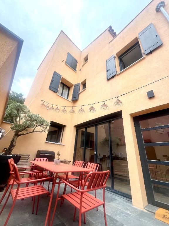 une table et des chaises rouges devant un bâtiment dans l'établissement Maison proche des Calanques de la Côte Bleue, à Ensuès-la-Redonne