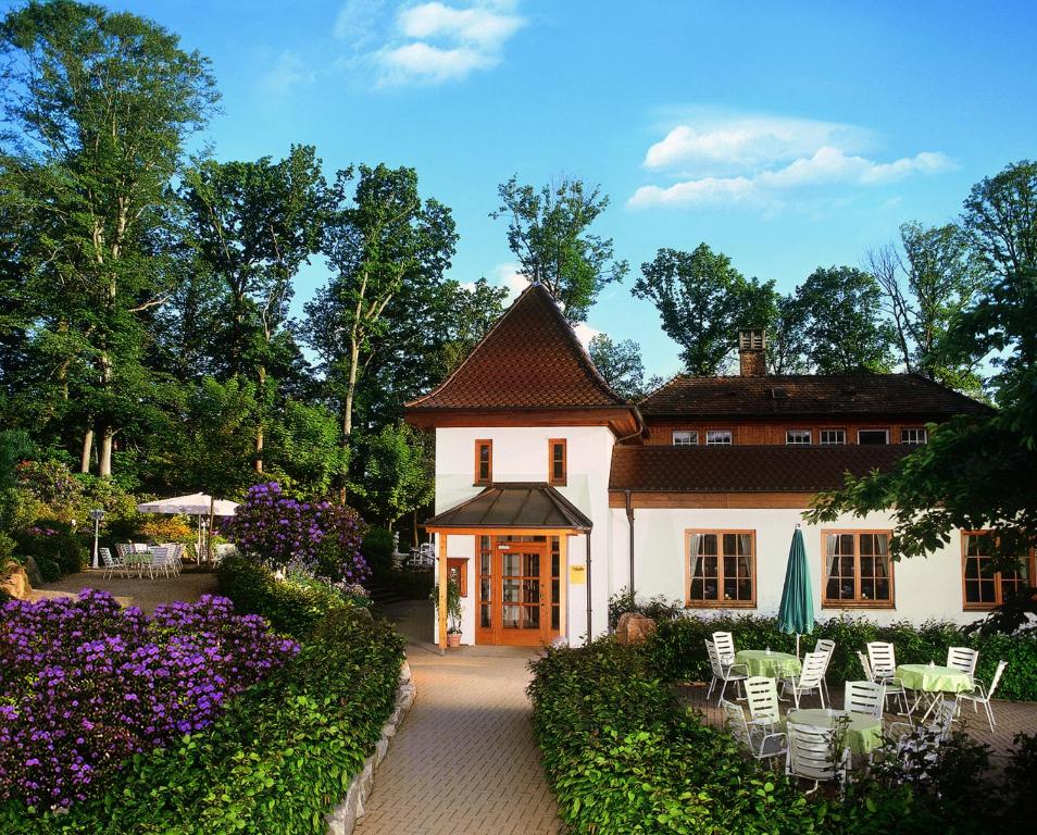 ein großes weißes Haus mit Stühlen und Blumen in der Unterkunft Waldcafé Hotel Restaurant in Baden-Baden