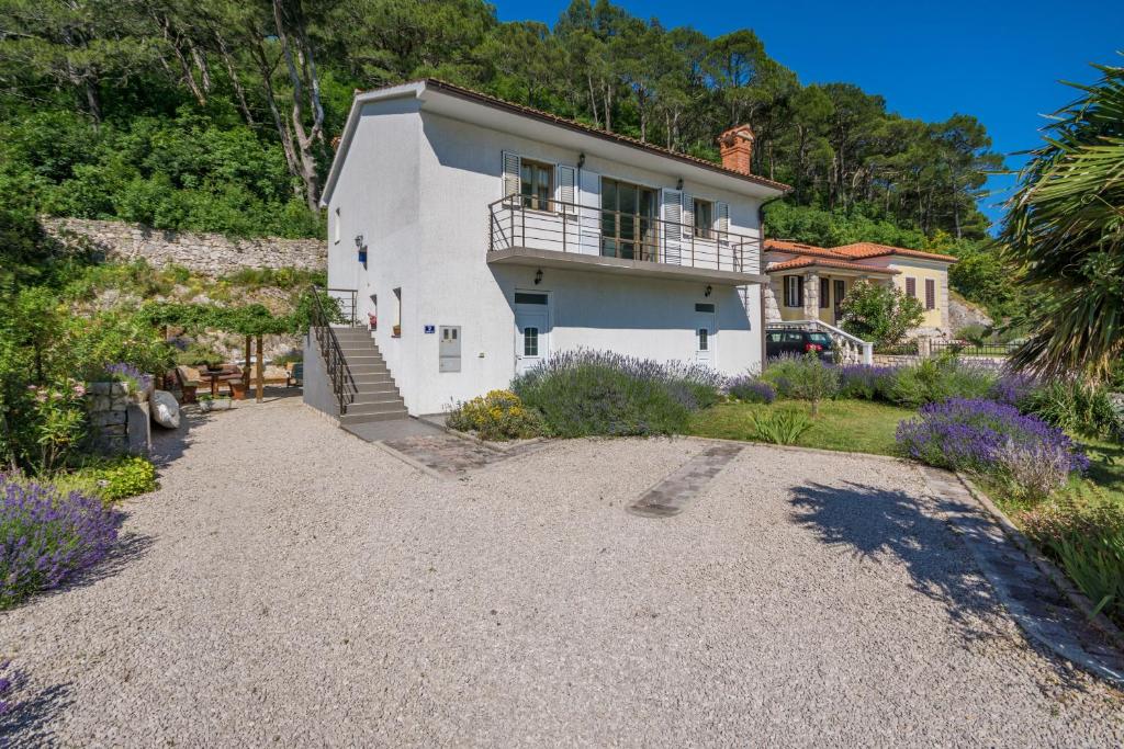 a white house with a balcony and a gravel driveway at Villa Dorijana, a beachfront holiday home in Plomin