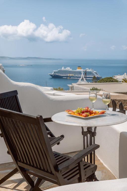 Una mesa con un plato de comida y dos copas de vino. en Villa Konstantin Rooms &amp; Suites, en Mykonos ciudad
