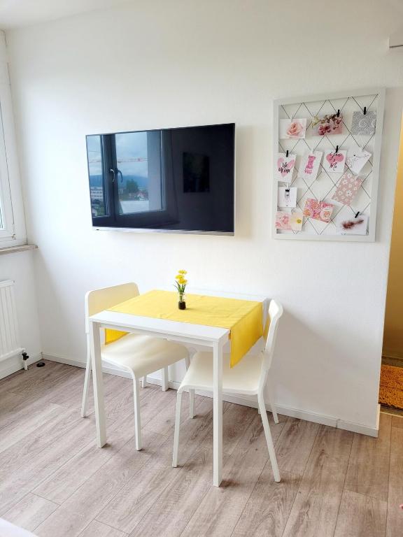 a white table and chairs with a yellow table and a tv at Mini Sun in Dornbirn