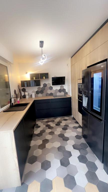 La cuisine est équipée d'un réfrigérateur noir et d'un sol en damier. dans l'établissement Apparemment Cosy proximité, à Saint-Denis