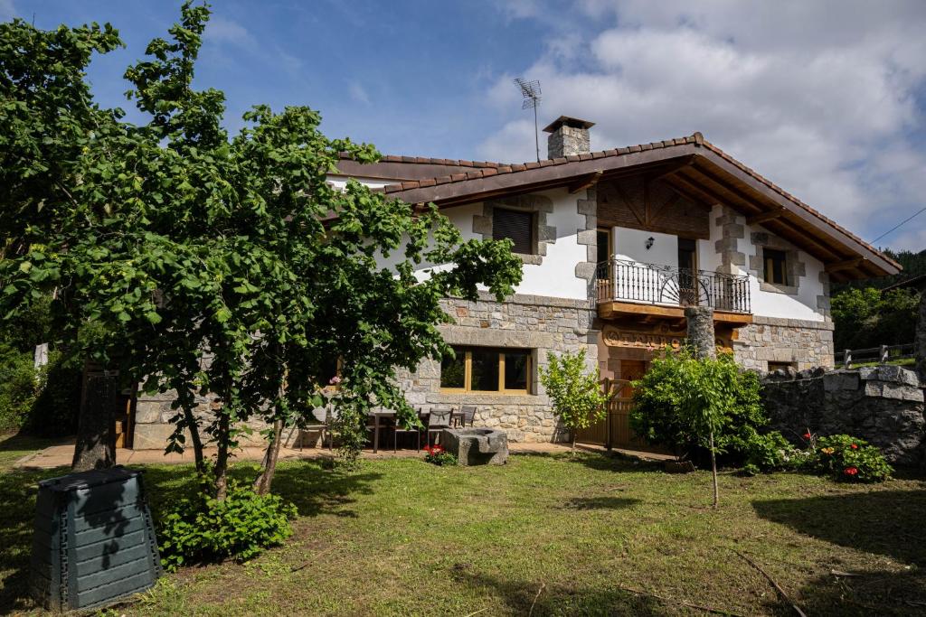 une maison en pierre avec un arbre devant dans l'établissement Tanbolin, à Gautegiz Arteaga