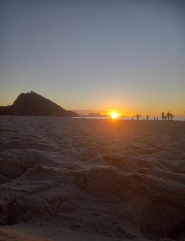a sunset on a beach with the sun setting at VILA LEME Casa 11 in Rio de Janeiro