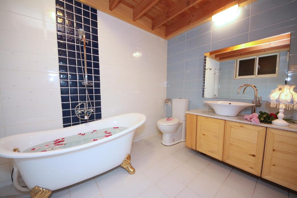 a bathroom with a tub and a toilet and a sink at Green Forest Villa in Yilan City