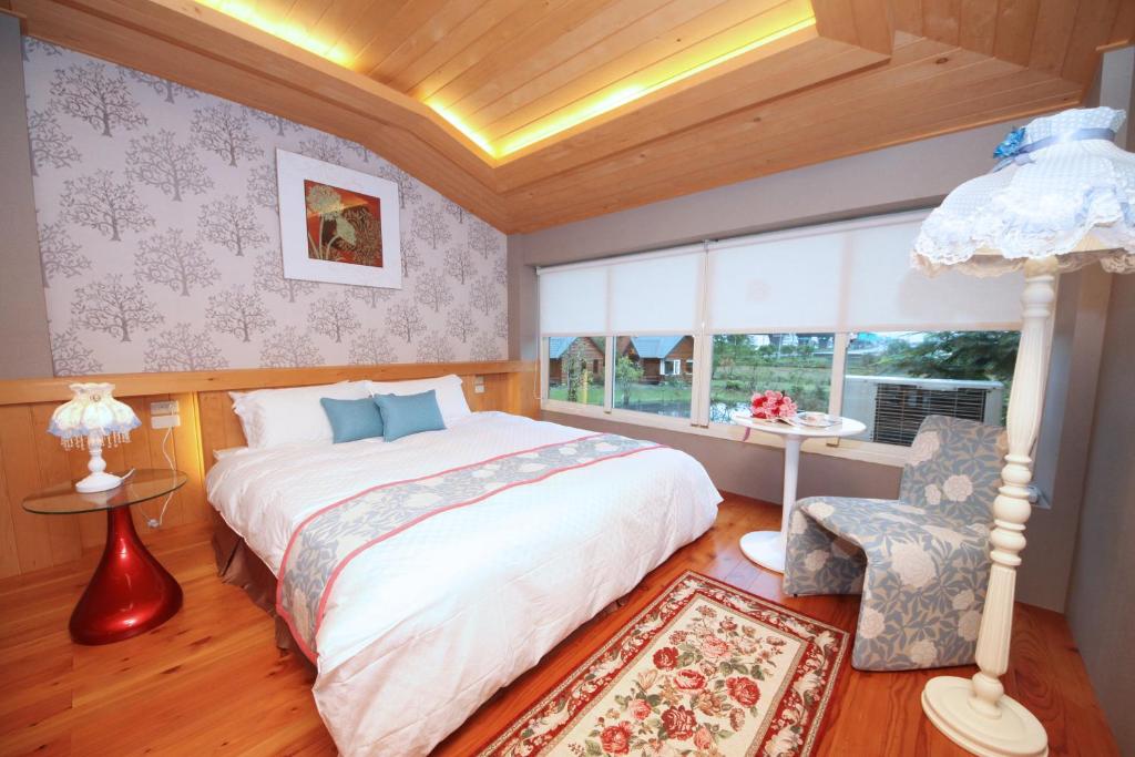 a bedroom with a bed and a chair and a window at Green Forest Villa in Yilan City