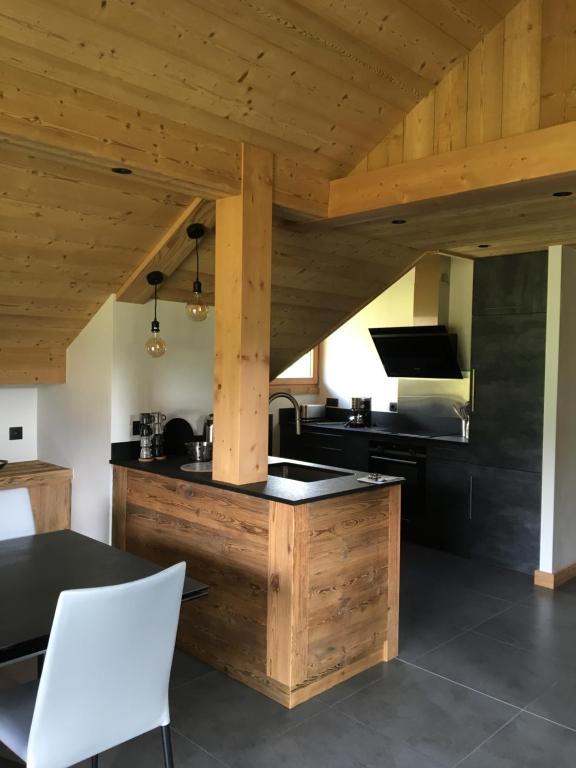 - une cuisine avec un plafond en bois, une table et des chaises dans l'établissement Les Séracs, à Combloux