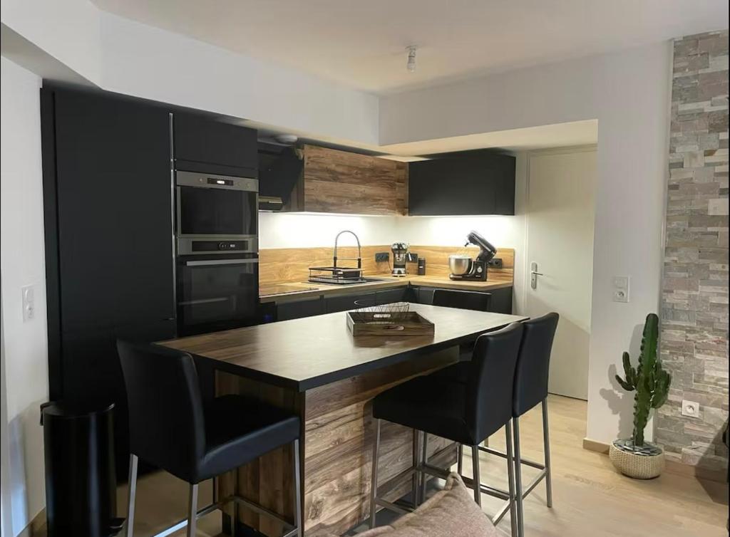 une cuisine avec des placards noirs et un îlot avec des tabourets de bar dans l'établissement Appartement T3, 5 minutes à pied des plages, à Ajaccio