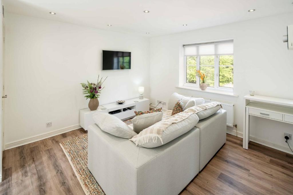 a white living room with a white couch at Loughton Hideaway: Cozy 1BD Near Tube & Nature in Theydon Bois
