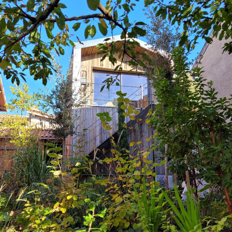 Un bâtiment avec beaucoup de plantes devant lui dans l'établissement Maison colorée dans un jardin, à Gaillac