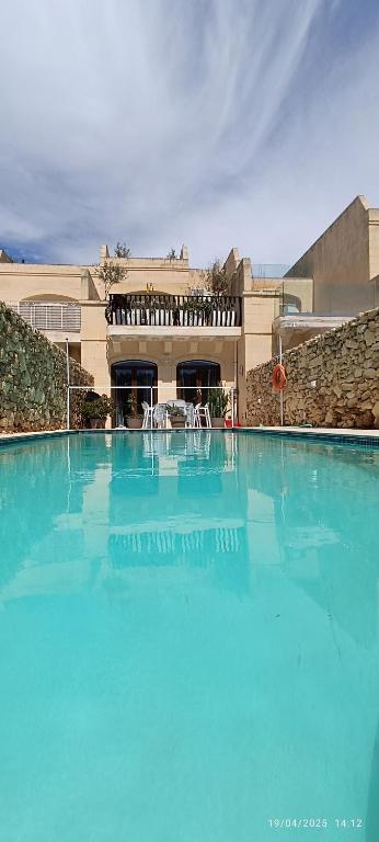 a large pool of blue water in front of a building at Azure in Għarb