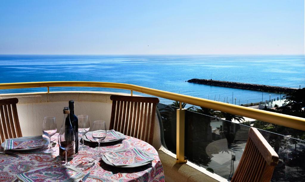 a table with wine bottles and glasses on a balcony at Sitges Apartamente frente al mar con piscina in Sitges