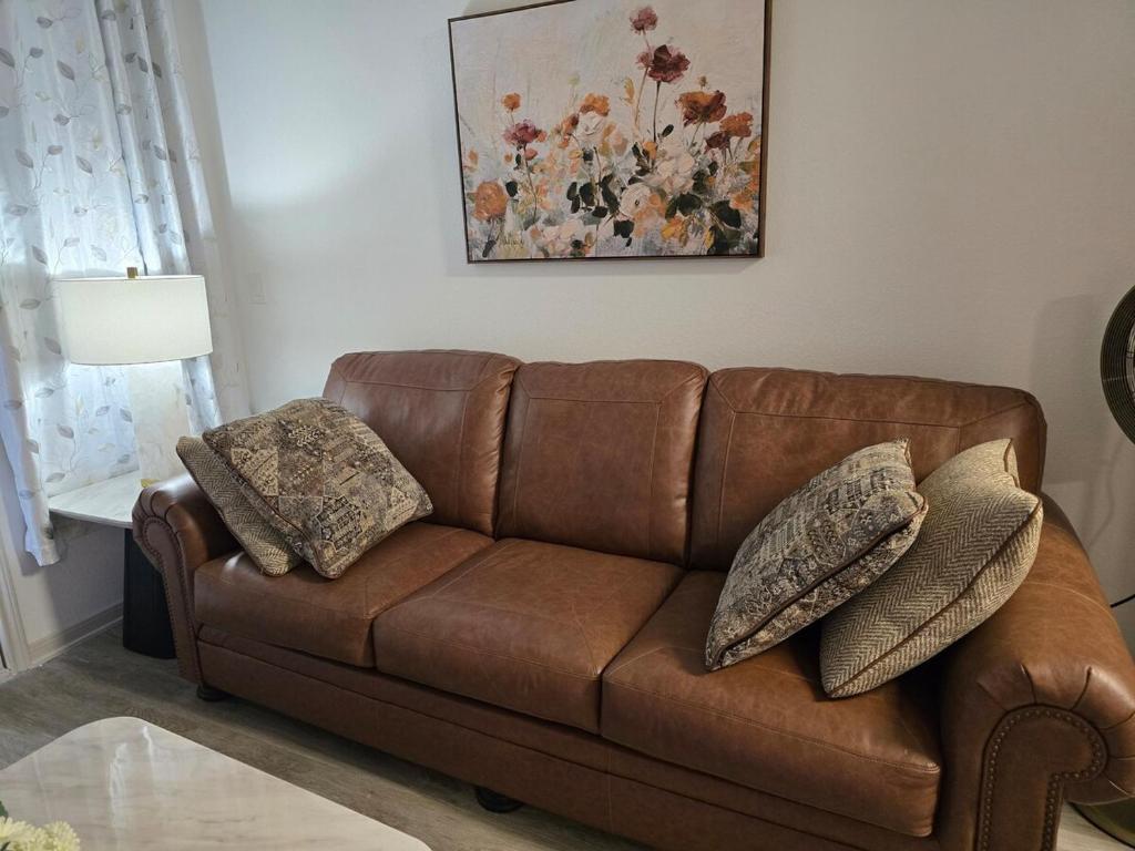 a brown leather couch with pillows in a living room at Comfy Apartment in Frisco in Frisco