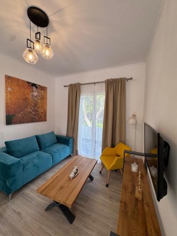 a living room with a blue couch and a table at Poseidon Garden View Apartment in Perivólion