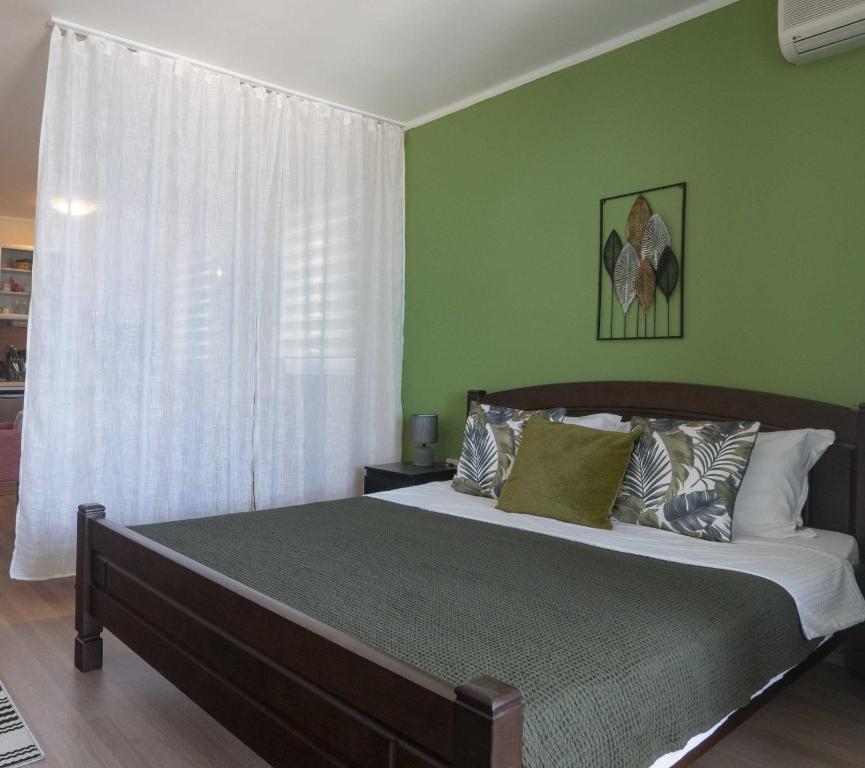 a bedroom with a bed with green walls and a window at Rosemary Terrace Krasici in Krasici
