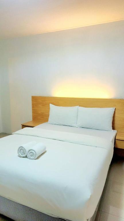 A simply furnished double bed with fresh white linens and rolled towels.