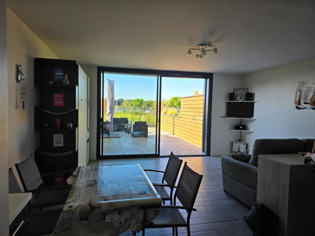 - un salon avec une table et une vue sur un patio dans l'établissement Appartement Lavoisier, à La Rochelle