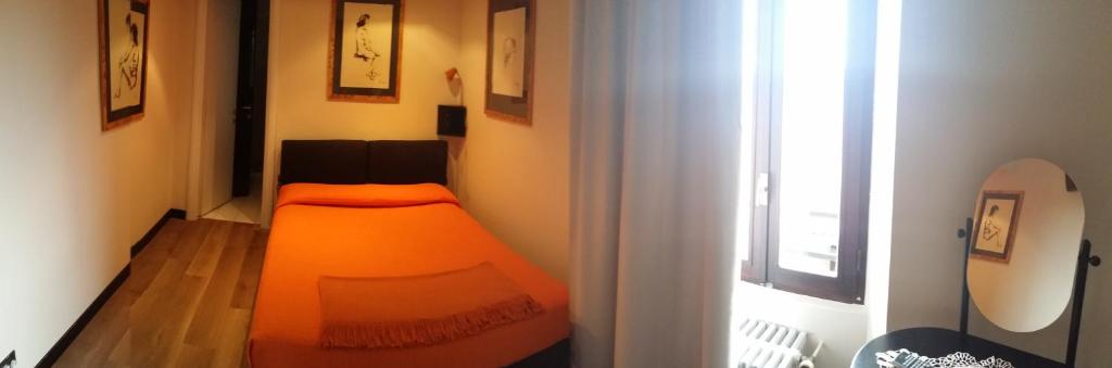 an orange bed in a room with a window at Il Castello B&B in Varallo Pombia