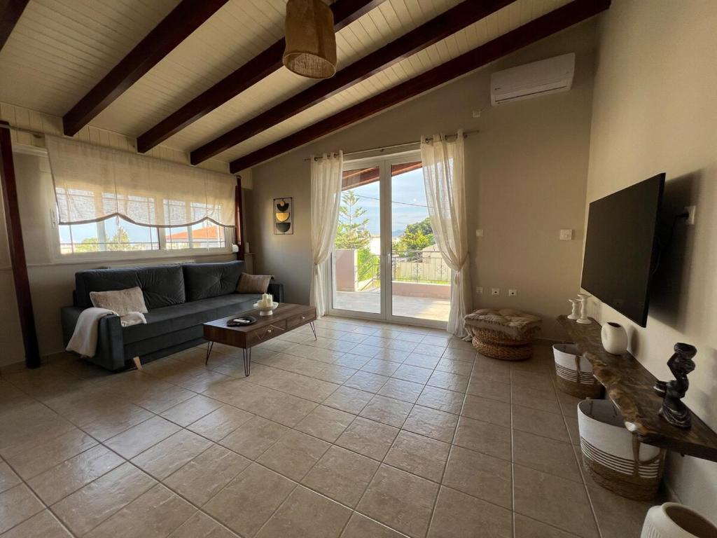 a living room with a couch and a tv at Lithos Apartment in Artemida