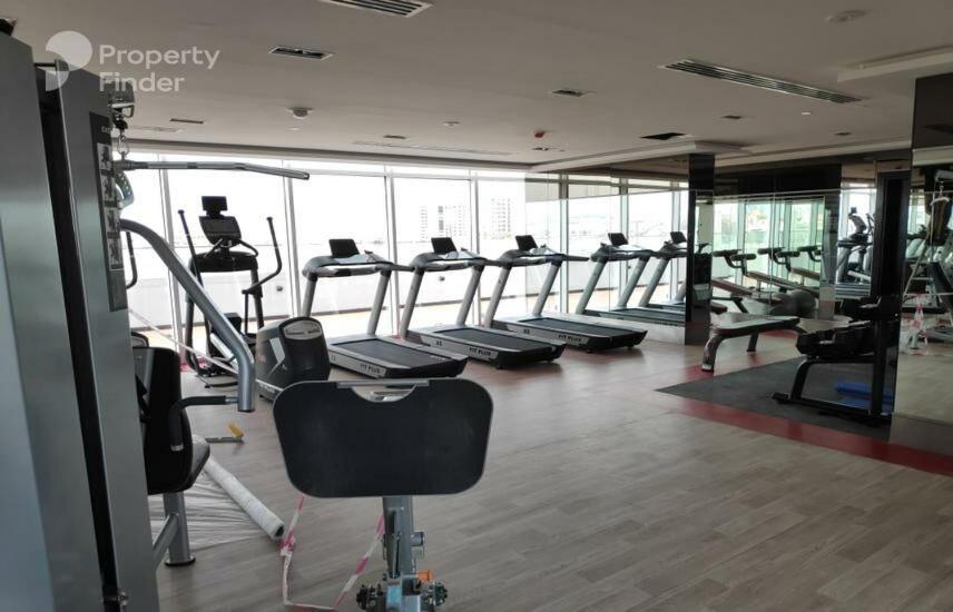 a gym with a row of treadmills and machines at Glamz studio staycation Dubai in Sabkhah