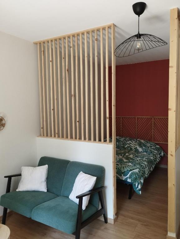 un salon avec un canapé vert et un lit dans l'établissement Studio climatisé et spacieux situé près des Parcs, à Vichy