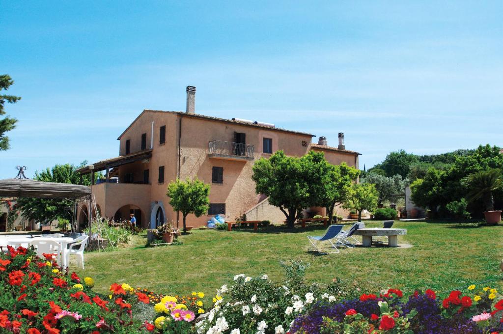 a house with a yard with flowers in front of it at Podere Giovanni in Castagneto Carducci