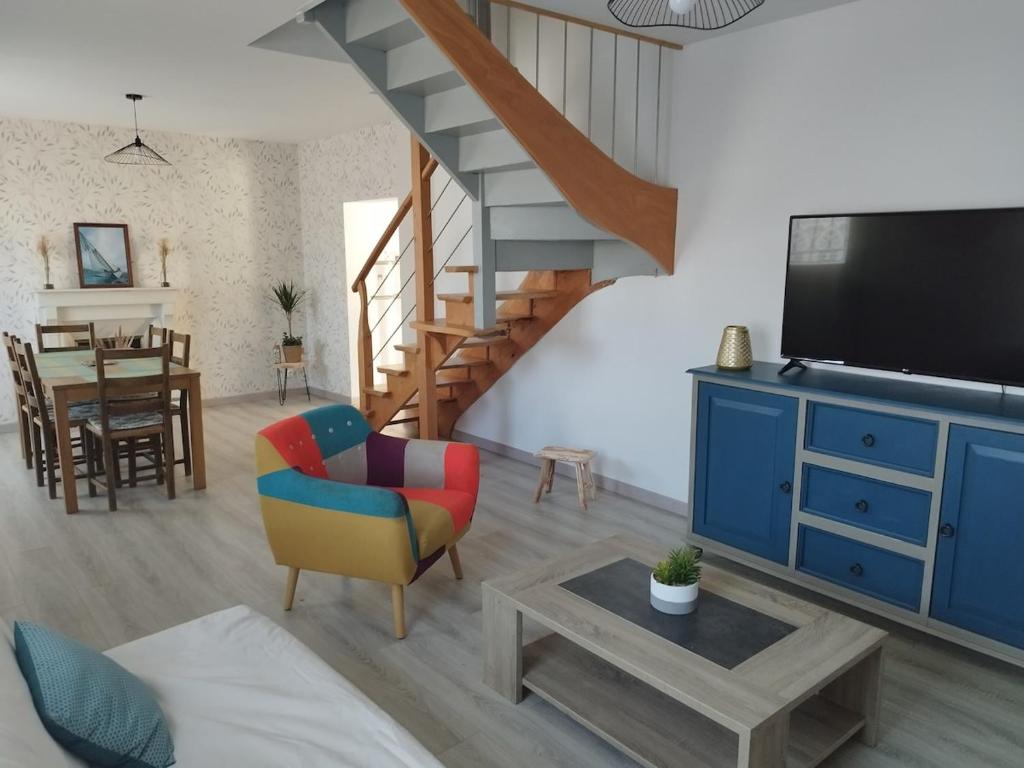 Il comprend un salon avec un escalier et une télévision. dans l'établissement Petite maison a deux pas du centre, au Faou