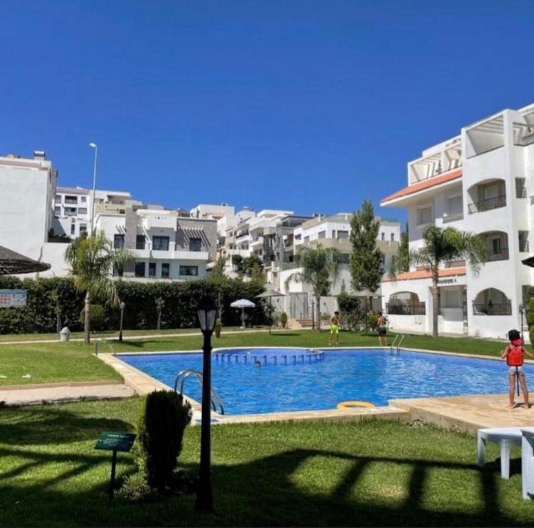 una persona in piedi vicino alla piscina in un resort di TANGER Appartement 3 Chambre Résidence Family 2 min plage a Tangeri