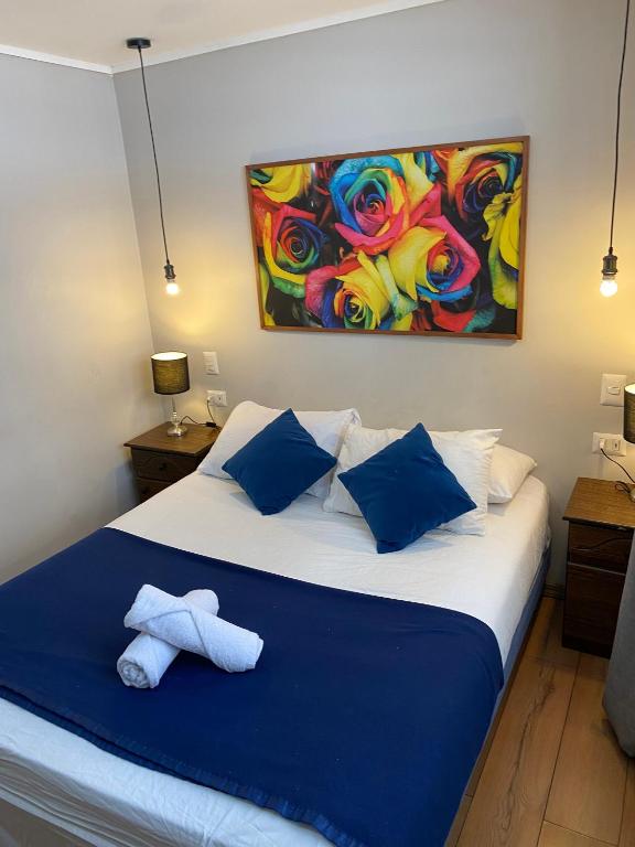 a bedroom with a bed with blue pillows and a painting at BB Casita Blue Hotel in Santiago