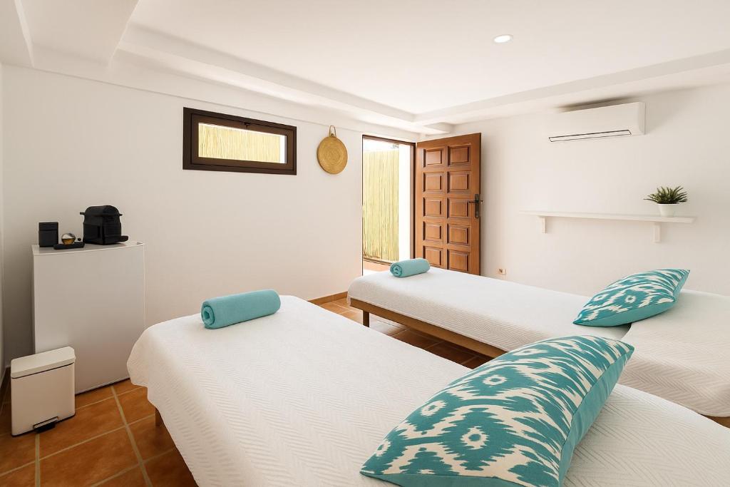 - 3 lits dans une chambre avec des murs blancs et des oreillers bleus dans l'établissement Habitación en el campo con baño privado en Puerto Pollensa, à El Port