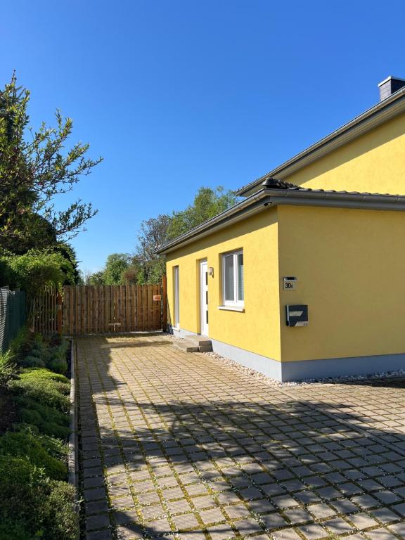 a yellow house with a fence and a brick driveway at Ferienwohnung Alte Brauerei in Leipzig