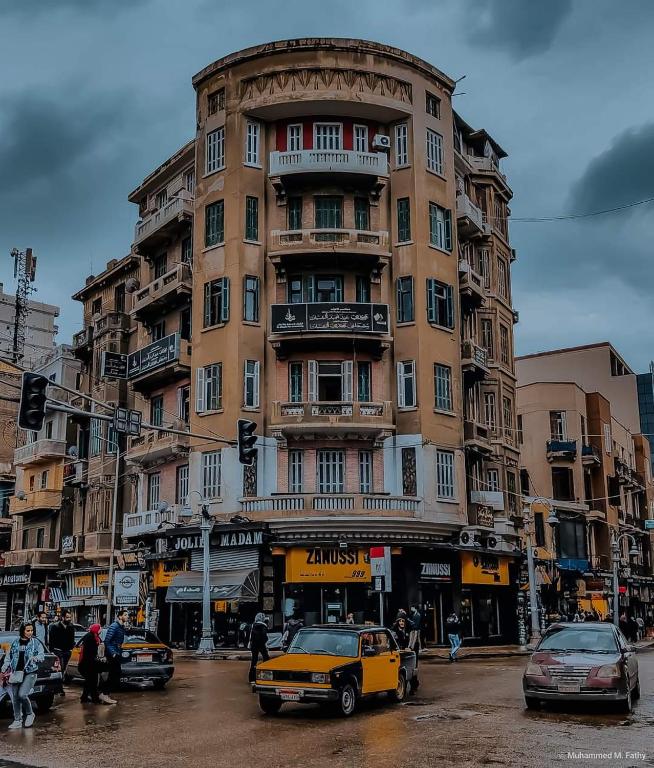 a yellow car parked in front of a tall building at Agora House for men only 仅限男性 in Alexandria