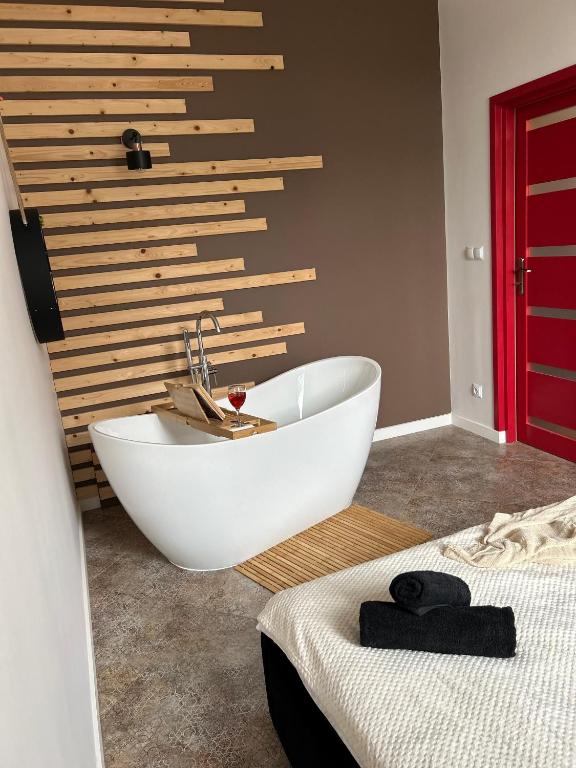 a bathroom with a white bath tub next to a bed at La Ville - Rouge in Zator