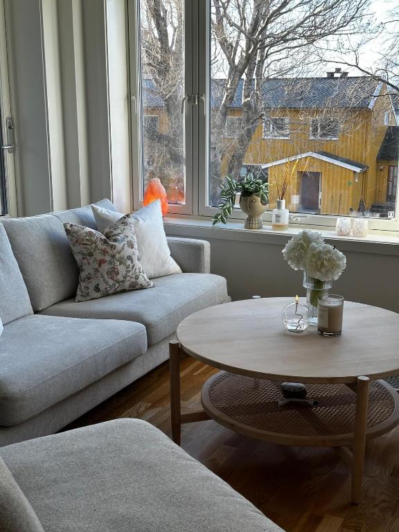 a living room with a couch and a table and a window at Sentrumsnær leilighet i Bodø in Bodø