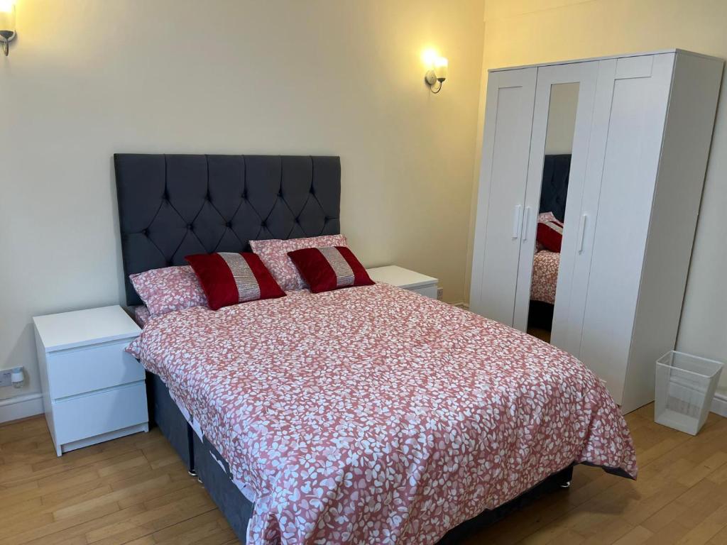 een slaapkamer met een groot bed met rode kussens bij SAI Residence in Ilford