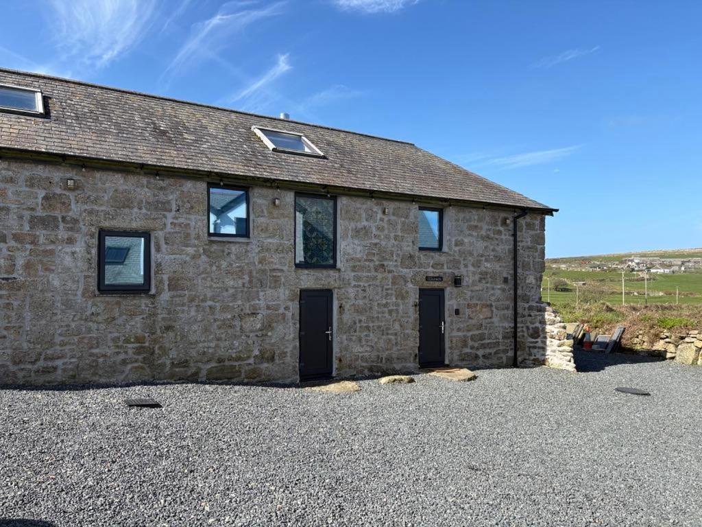 a stone house with a gravel driveway in front of it at Wonrek in Penzance