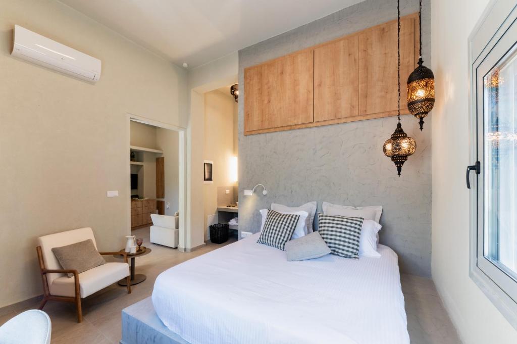 a bedroom with a large white bed and a chair at Lemontrees Residences in Rhodes Town