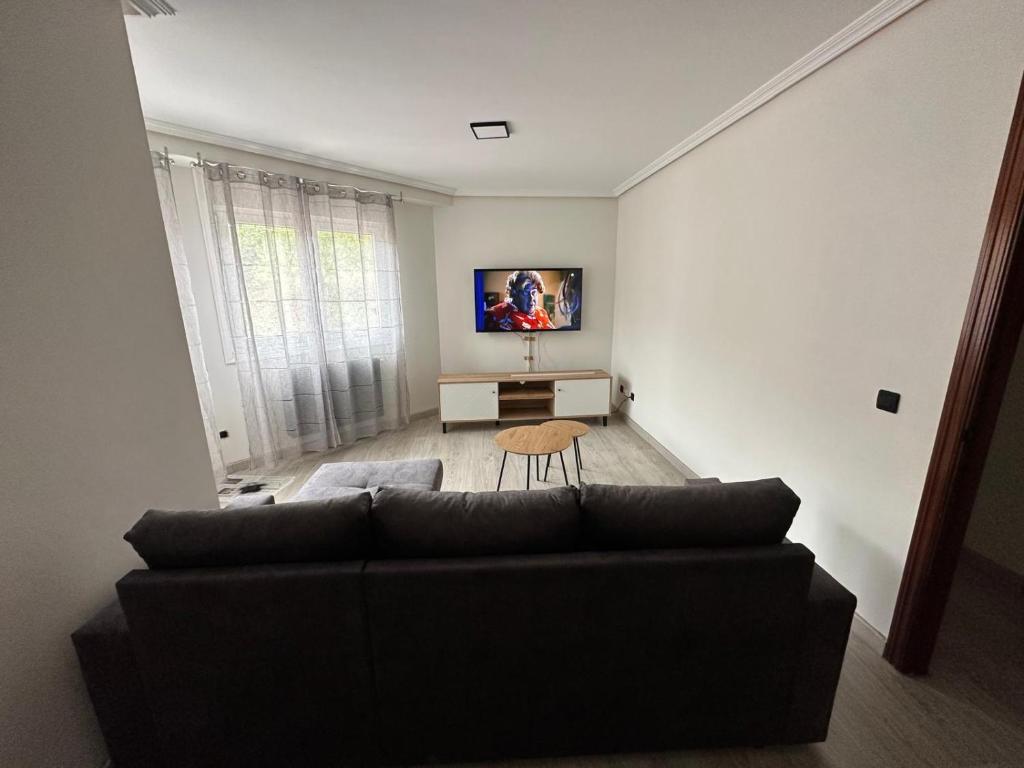 een woonkamer met een zwarte bank en een tafel bij Luanco para vivir y disfrutarlo VUT7223AS in Luanco