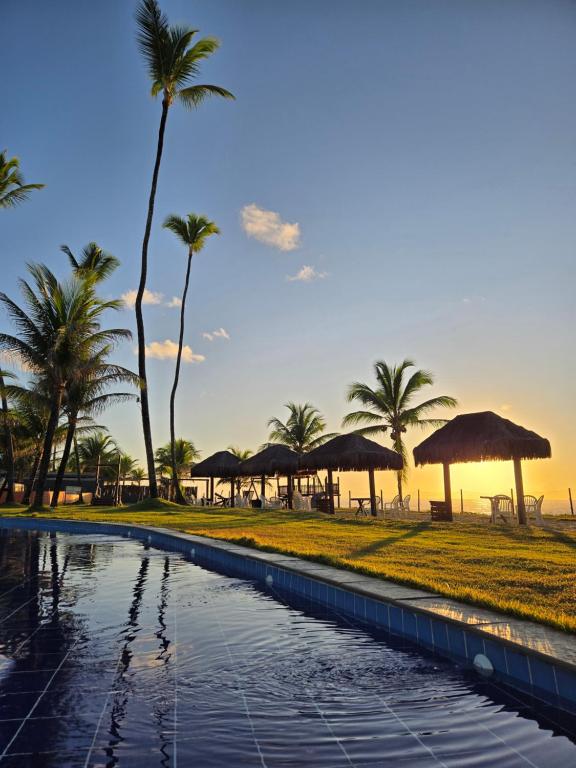 a pool at the beach with palm trees and umbrellas at Best location of the development, ground floor seafront in Porto De Galinhas