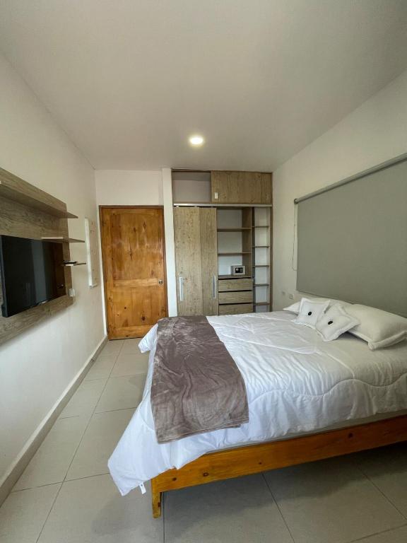a bedroom with a large bed and a flat screen tv at Mar, Hamaca, BBQ y Cocina, Hogar Entre Olas in Puerto Colombia