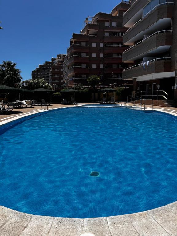 a large blue swimming pool in front of a building at Apartamento Vacacional Oropesa del Mar primera línea in Oropesa del Mar