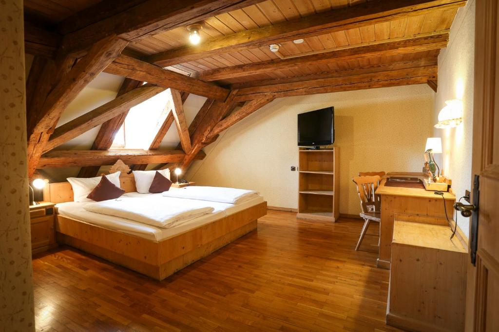 a bedroom with a bed and a desk with a television at Hotel-Brauereigasthof Josef Fuchs in Neusäß