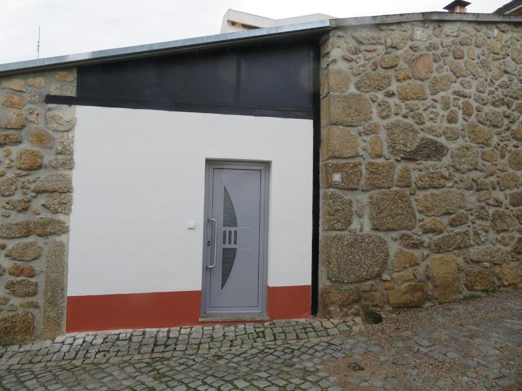 a white garage with a door in a stone building at Casa do Cortinhal in Covilhã