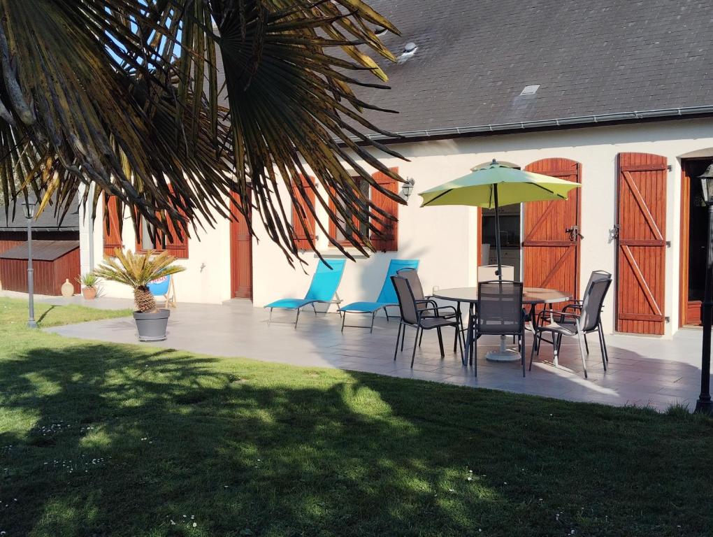 a patio with a table and chairs and an umbrella at Villa évasion in Ambillou