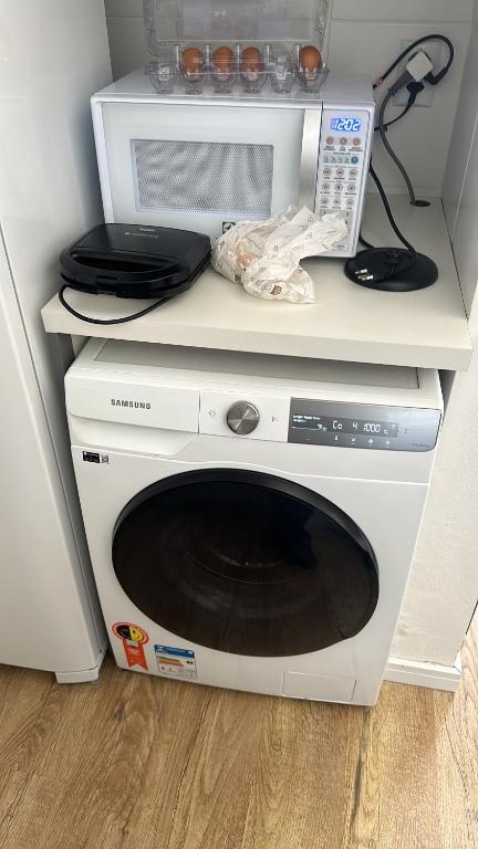 a microwave oven sitting on top of a white cabinet at Loft no Centro Completo com Box in São Leopoldo