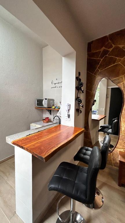 a kitchen with a counter with black leather bar stools at Aconchego BH in Belo Horizonte