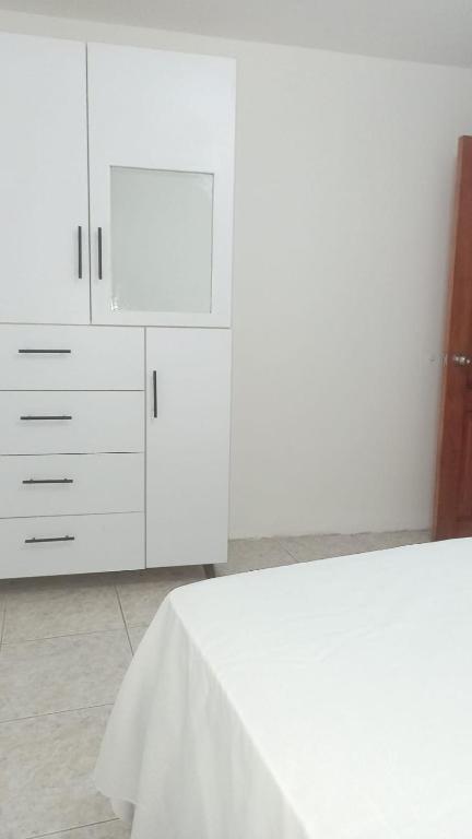 a white kitchen with white cabinets and a table at Apartamento vacacional in Manta