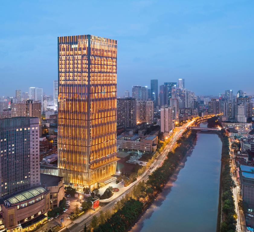 un edificio alto junto a un río en una ciudad en Wanda Reign Chengdu, en Chengdú