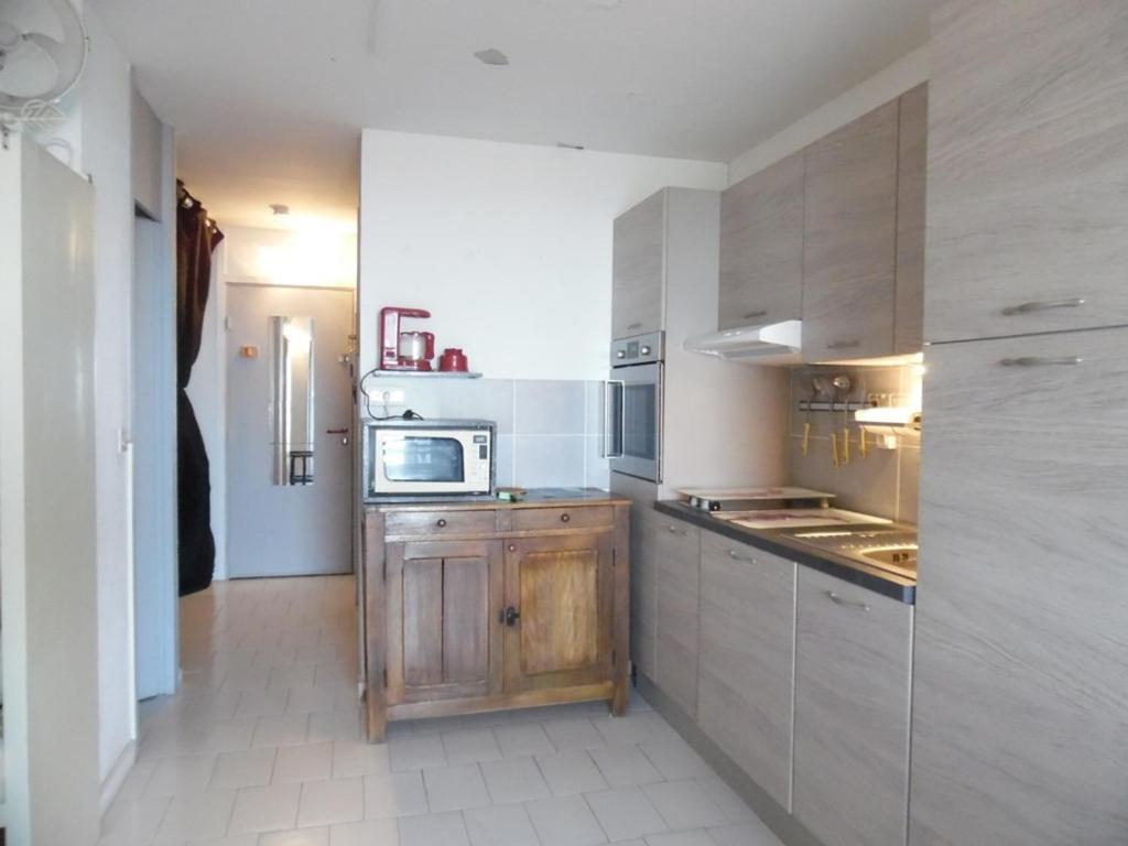 La cuisine est équipée d'une armoire en bois et d'un four micro-ondes. dans l'établissement Studio cabine vue mer, WiFi, parking sécurisé - FR-1-750-81, à Canet